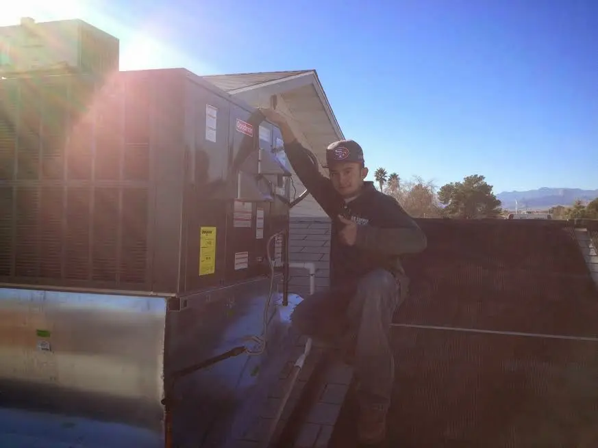 HVAC technician performing AC Tune-Up on a rooftop unit in Brush